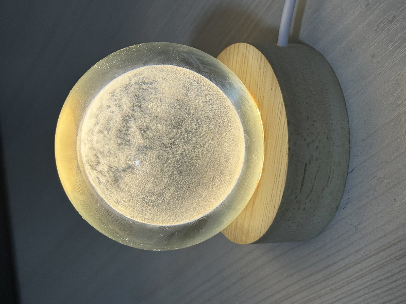 A glowing moon lamp on a round wooden base.